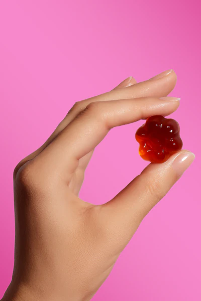 dłoń trzymająca żelkę so bloomy o kształcie różowego kwiatka